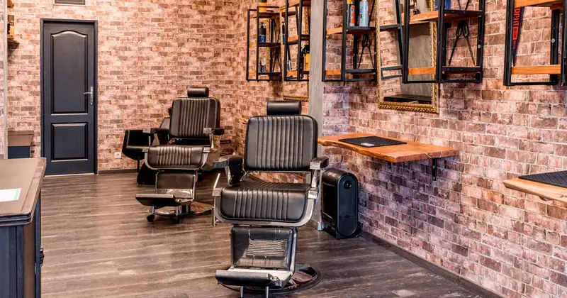 Stylish barber shop interior featuring black leather chairs and rustic brick walls for a contemporary look.