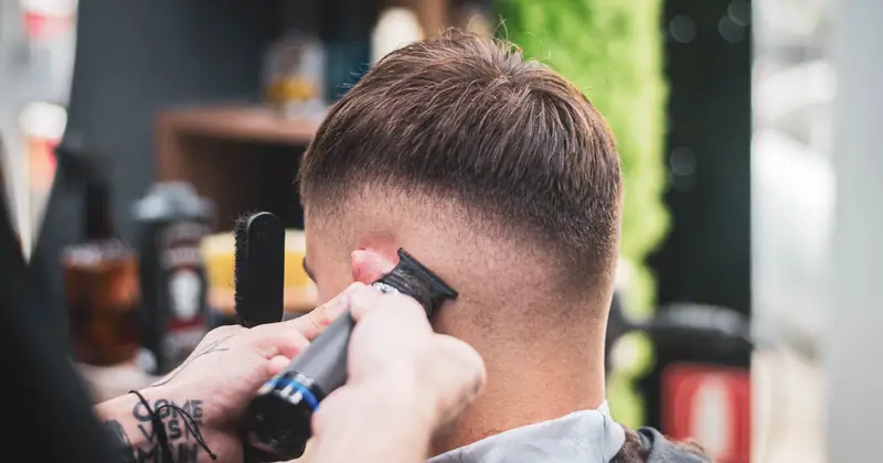Barber using clippers to finish a fade haircut
